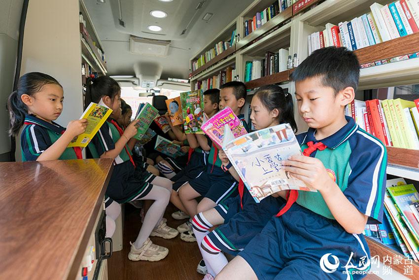 内蒙古呼和浩特市玉泉区恒昌店巷小学的孩子们在“流动图书车”内翻阅图书。