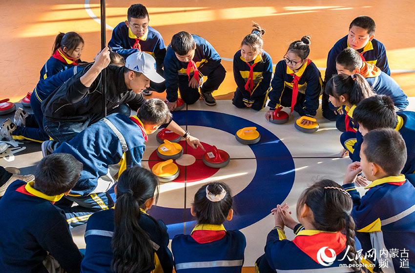 呼和浩特市玉泉区巧尔齐召小学的教练在指导学生学习旱地冰壶。