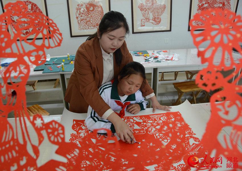 河北邢台市襄都区祝村中心学校祝村小学美术教室宋琪指导学生进行刻纸创作。 刘栋摄