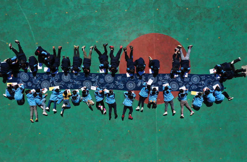 5月17日，小学生在贵州省丹寨县龙泉镇羊甲小学课后服务中学画苗族传统蜡染图案（无人机照片）。