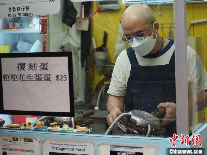 图为店主新哥正在制作本土美食鸡蛋仔。 中新社发 刘雨婷 摄