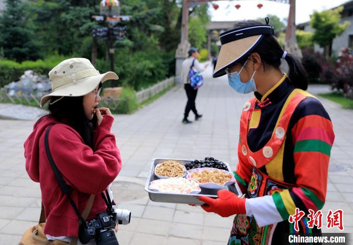 图为身穿土族服饰的女性介绍当地特色小吃。　薛蒂 摄