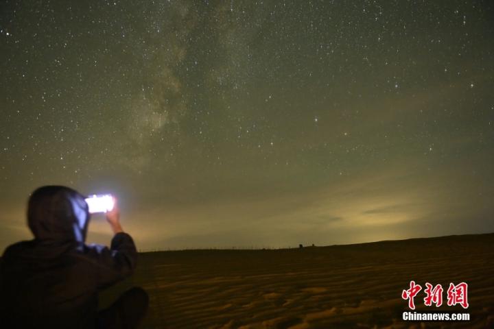 9月13日深夜，甘肃省武威市民勤县苏武沙漠大景区腹地摘星小镇内，游人拍摄星空。