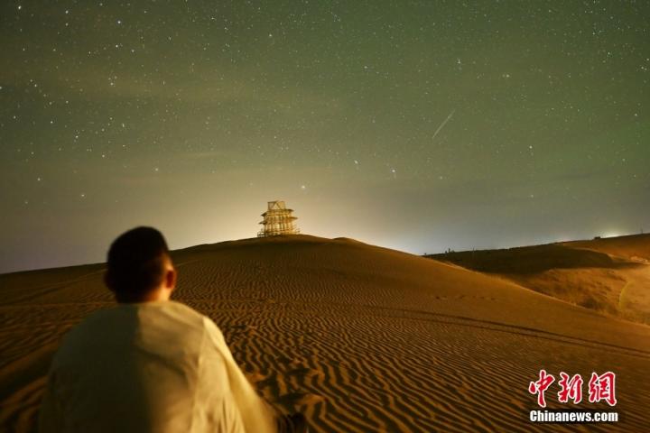 9月13日晚，甘肃省武威市民勤县苏武沙漠大景区腹地摘星小镇内，游人观看流星。