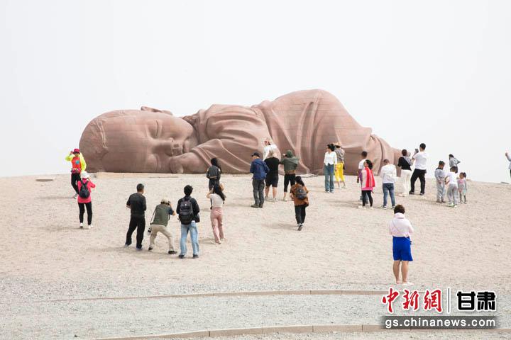 图为游客在瓜州戈壁国际雕塑艺术长廊参观大型雕塑《大地之子》。 崔小曼 摄