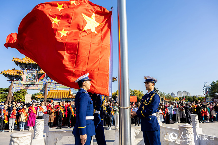 10月1日，道德模范、新时代好少年和最美志愿者等代表在呼和浩特市玉泉区塞上老街文化旅游休闲街区参加国庆节升旗仪式。丁根厚摄