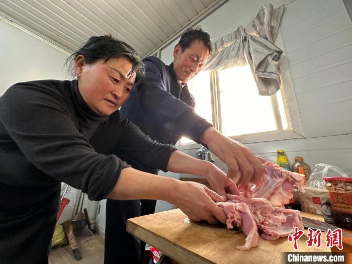 图为肖红坪村村民樊胜平和爱人在板房内为年夜饭“手抓羊肉”做准备。王牧雨 　摄