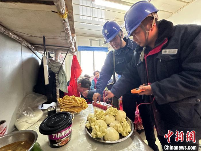 图为马玉(左一)和同事在检查村民板房内的安全用电情况。王牧雨 　摄