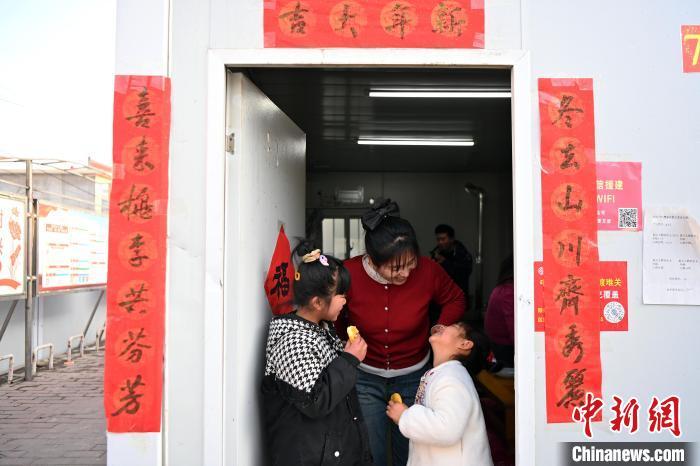 2月8日，甘肃省临夏州积石山县，民众逛集市、买年货、做美食，迎接中国农历新年的到来。图为积石山县石塬镇肖红坪村安置板房内小朋友正在吃新炸的油饼。九美旦增 摄