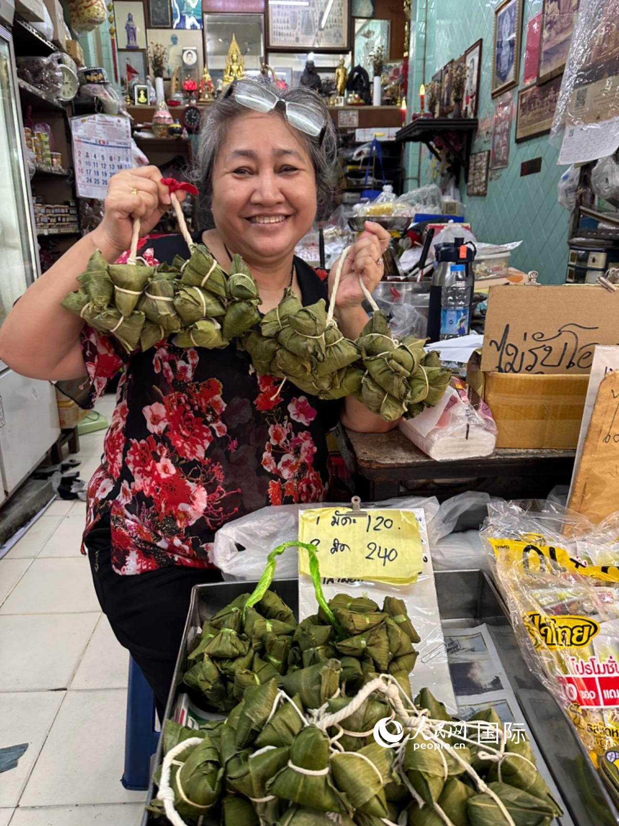 商家向顾客介绍“吉掌”（粽子的一种，一串一串，个头较小）。人民网记者 简承渊摄