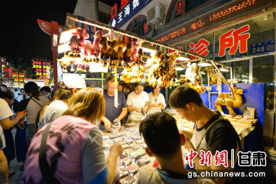 图为游客在敦煌夜市选购敦煌特色旅游工艺品。王斌银 摄