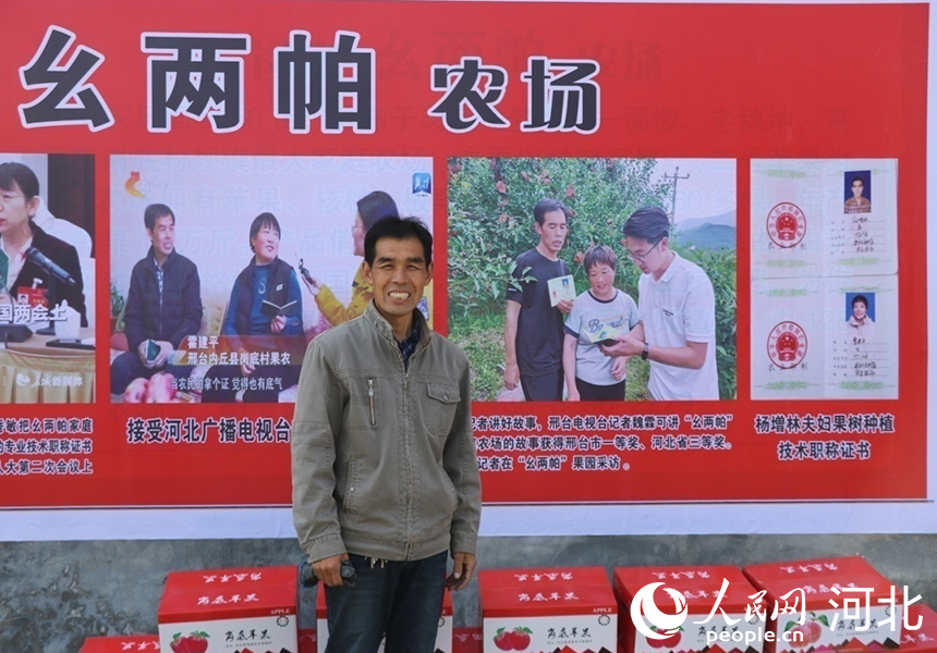 杨增林站在自己家农场广告牌前，职称证书成卖点。人民网记者 祝龙超摄